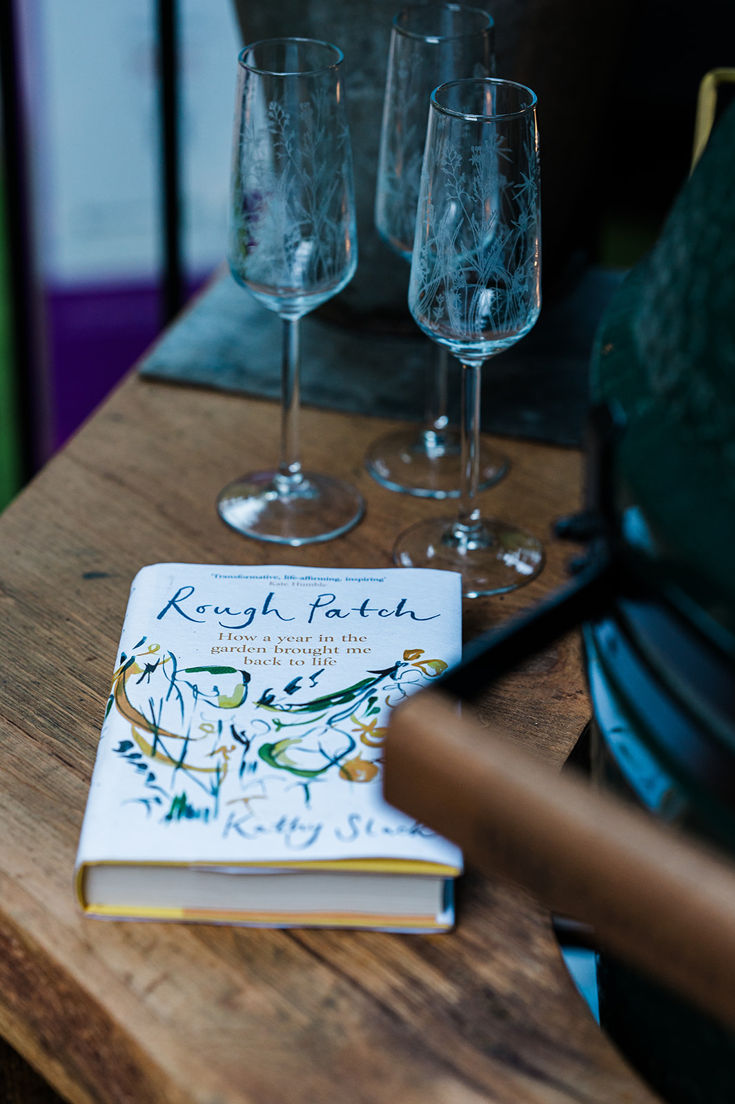 Emma Britton Meadow Glassware Flutes in Tales of the Riverbank Garden with Kathy Slack's book, Rough Patch.
